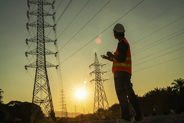 High Voltage Tower and Power Lines with Engineer Silhouette at Golden Hour