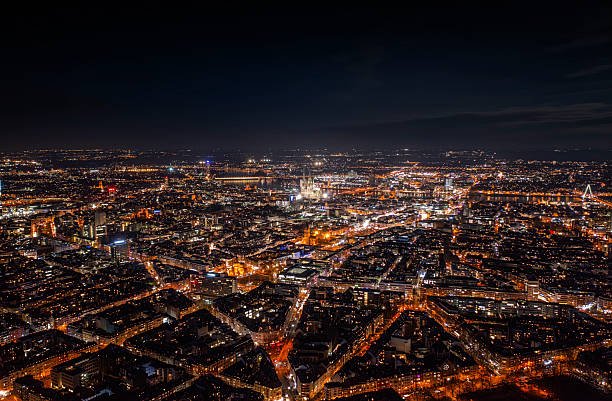 Aerial night view of the city of Cologne in western Germany, with an illuminated urban grid stretching across the Rhine metropolis. Streets, neighborhoods, and distant landmarks glow under city lights, showcasing the scale of a major European city and its nighttime infrastructure. North Rhine–Westphalia, Germany, Europe.